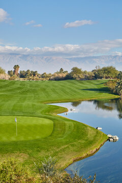 A beautiful golf course with perfectly manicured fairways, greens and a blue pond in the California desert in winter