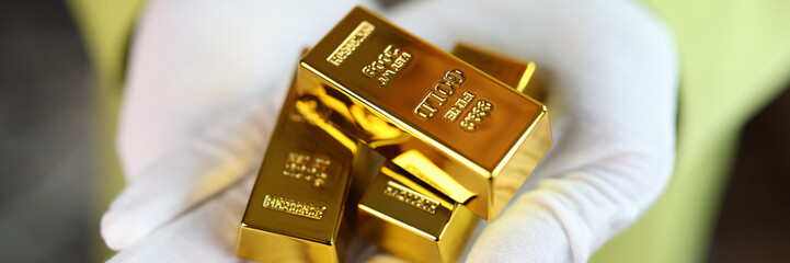 Close-up of man holding gold bars in his hands.