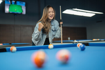 happy female pool player clenched her arms after poking the billiard ball during the billiard games