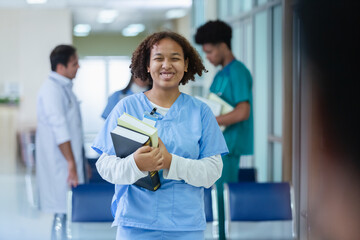 Portrait of happy smiling woman medical student holding school book have group students on...