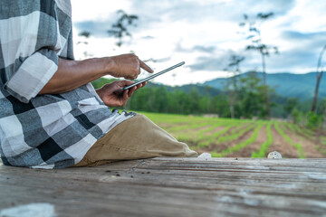 Close up of farmer's hands holding and working on tablet in corn field.