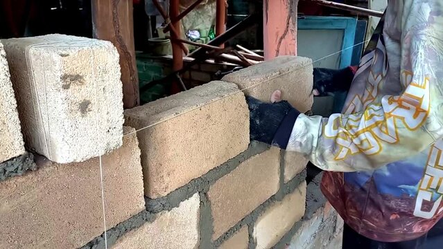 Activities Of A Builder Who Is Installing, Compiling And Tidying Bricks Using A Waterpass