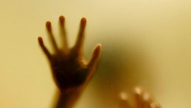 spooky ghost hand waving and scratching hands behind the frosted glass scary