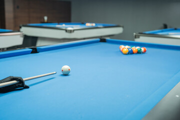 the hand of billiard player poking the white ball using the stick while starting the billiard game