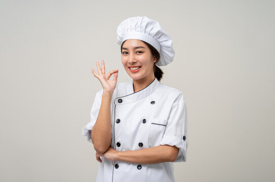 Young beautiful asian woman chef in uniform posting okay taste delight delicious hand gesture on isolated background. Cooking woman Occupation chef or baker People in kitchen restaurant and hotel.
