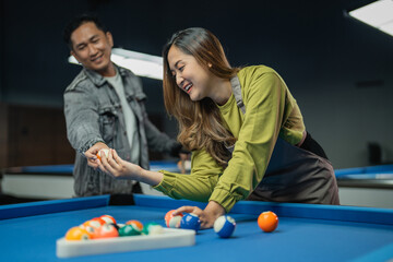 female pool table worker helps player arranging the balls with triangle rack