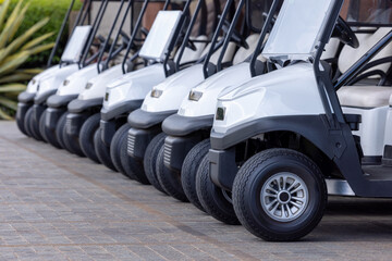  Golf cars in a row outdoors on a golf course. A row of empty golf carts on a golf course. golf course carts cars at luxury resort sport venue.All lined up ready for a tournament on a course.