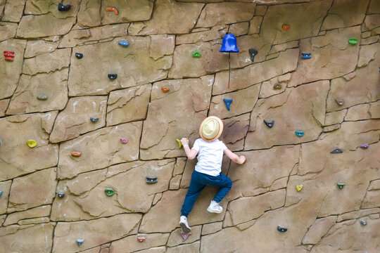 The boy is engaged in rock climbing.