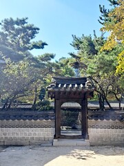 Tile capped wooden gate of traditional Korean architecture Hanok and main building seen through the gate in old small palace built in 19th century during the Chosun dynasty