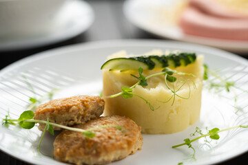 Mashed potatoes with meat cutlets on plate on black wooden background. Children's menu at the restaurant