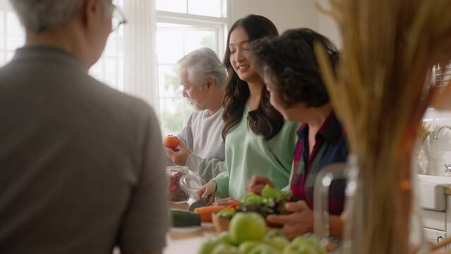 Group of Asian elder people friends making vegetables salad and fruit juice with her daughter in kitchen at home.concept of Group asia senior people Healthy eating,colorful fruits and vegetables.