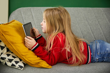 Smiling girl holding tablet PC and reading book