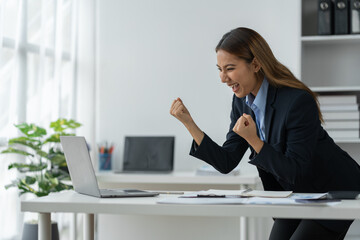 Confident Asian businesswoman smiling happy expression While using a laptop at work to start a successful small business and thrive financially.