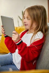 Smiling girl holding tablet PC and reading book