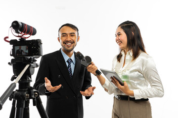 Obraz premium an adult men in black suit talking to the camera while interviewed by a beautiful female journalist using a microphone