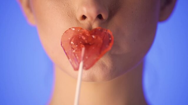 Woman kissing a heart shaped lollipop