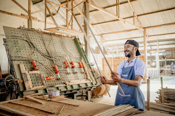 Naklejka na ściany i meble male carpenter checking wood materials before working in a wood craft workshop