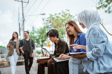 Group of young students studying using a laptop sitting in an outdoor cafe