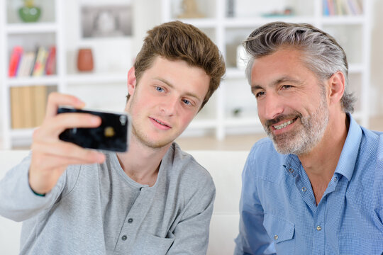 Adolescent boy talking photo of himself with his father