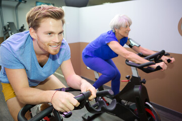 group with senior woman spinning on fitness bikes