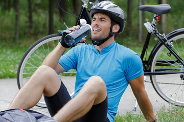 Naklejka premium male mountain biker drinking water in the forest