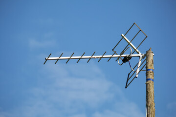 Homemade television antenna against the blue sky. Attached to a pole.