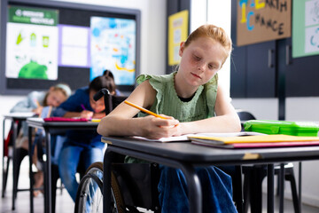 Caucasian schoolgirl in wheelchair with diverse schoolchildren in school classroom