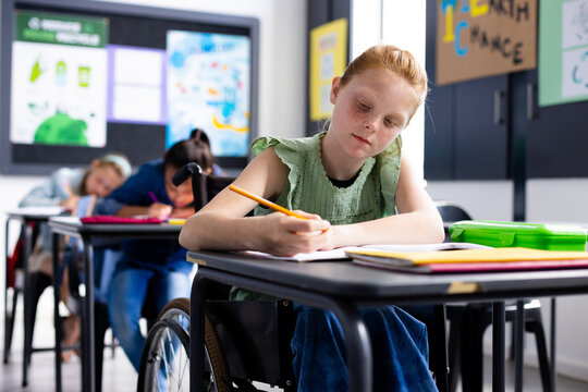 Caucasian schoolgirl in wheelchair with diverse schoolchildren in school classroom - Powered by Adobe