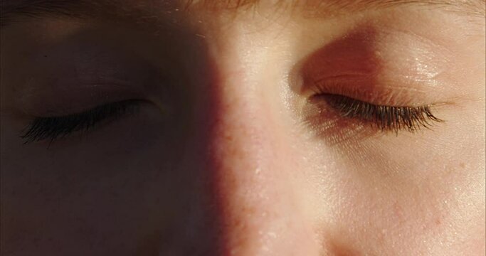 Close-up shot of woman brown eye with light make-up opening and looking at the sun slow motion. The red-haired girl's eyes open. Slow motion. 120FPS. Macro eye photography. The face of a beautiful