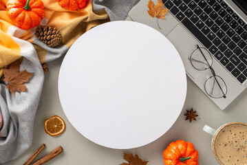 Comfortable workplace at home concept. High angle view photo of laptop with glasses, autumn decorations, warm blanket and mug of hot chocolate on grey isolated background, copyspace inside a circle