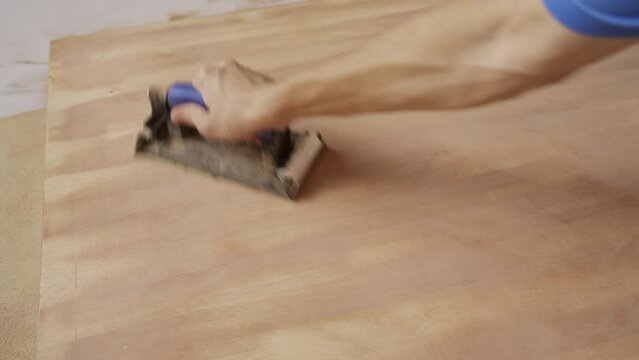 Sanding wooden table with sandpaper holder
