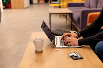 Card holder lies on wooden table next to programmer typeing on the lap top