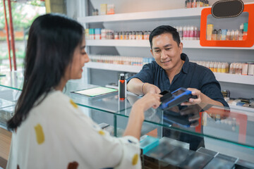 Obraz premium female customer paying the stuff using the credit card at the vape store