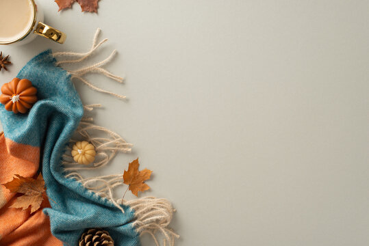 Experience the cozy bliss of autumn at home with this top view photo. Hot coffee, warm blanket, pumpkin candles and maple foliage set the empty space for text or advert on isolated grey background