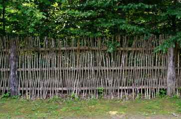 Wattle is a lightweight building material made by interlacing branches. Wattle fence against the...