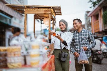 beautiful muslim couple are shopping in a food stall or street vendor during ramadan