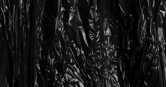 Dive into the captivating world of textured stretched plastic film against a black canvas, mirroring the intriguing folds and creases akin to rumpled cellophane wrap often used to wrap food products.