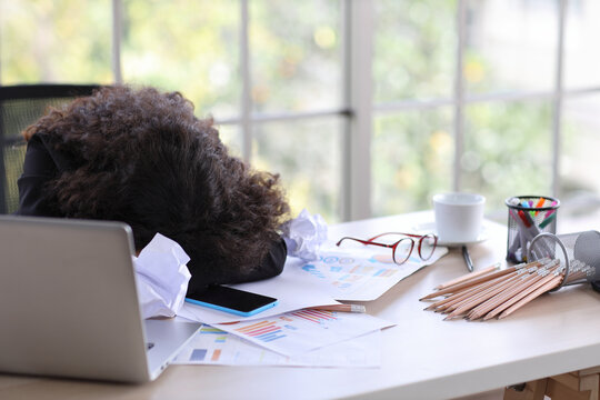 Mid adult businesswoman lying face down on table in office after bad news business failure or get fired and feeling discouraged, distraught, distraught and hopeless in modern office.