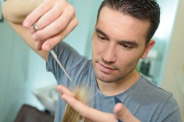 closeup of male hairdresser trimming end of hair