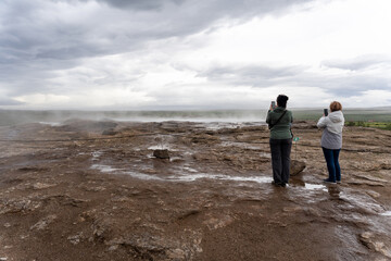 Tourists taking photos of The Great Geysir in Iceland
