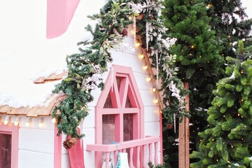 Frosted window sill with christmas decoration. Winter holiday home, view from outdoors. Fir tree garland on wooden board of front yard facade house. New Year festive decor of the streets