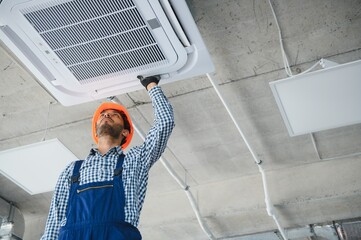 Professional technician maintaining modern air conditioner indoors. Space for text