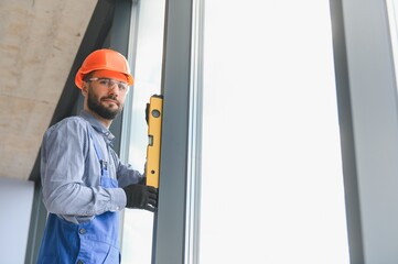 Worker installing plastic window indoors.