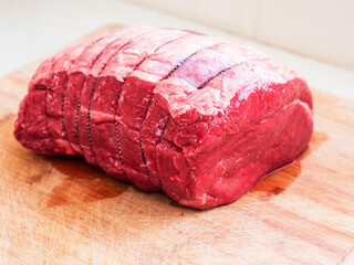 Big size beef top side joint on a wooden cutting board. Premium high quality meat. Traditional meal for a big family dinner. Light and airy look.