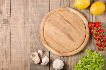 Wooden Cutting Board with Fresh Herbs and Raw Vegetables on Rustic Wood Table. Top view. Cooking background.