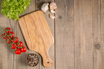 Wooden Cutting Board with Fresh Herbs and Raw Vegetables on Rustic Wood Table. Top view. Cooking background.