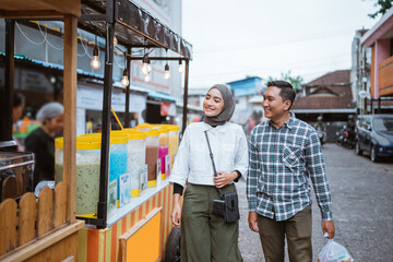 beautiful muslim couple are shopping in a food stall or street vendor during ramadan