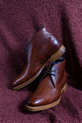 Mens Footwear Concepts. Pair of Stylish Modern Calf Leather Brown High Boots Shoes Placed Over Fabrics Grunge Background.