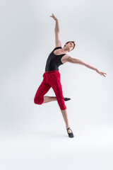 Ballet Sport Ideas. Contemporary Ballet of Flexible Athletic Man Posing in Red Tights in Dance Pose With Hands Lifted in Studio on White.