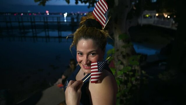 woman posing for picture with american flags at night